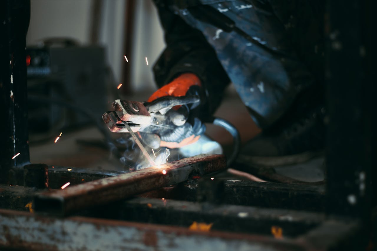 Focused shot of a welders hands holding an electrode while sparks fly during metalwork.