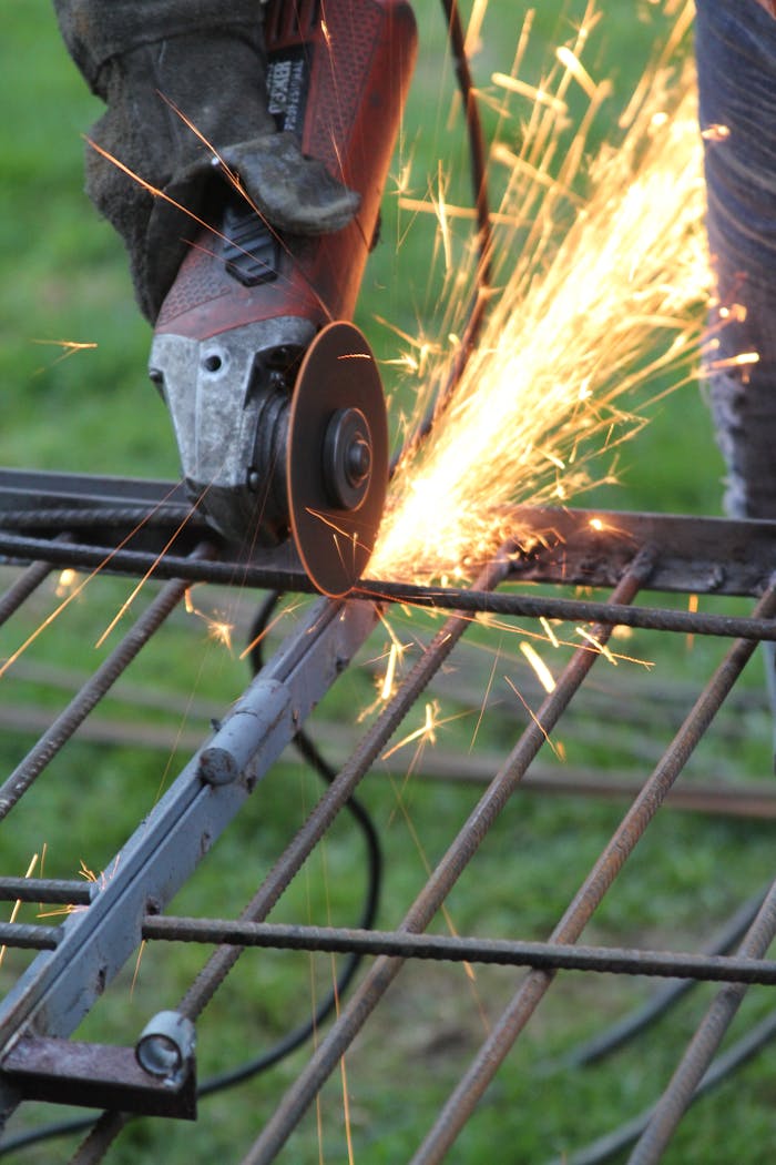 Detailed view of an angle grinder cutting metal, producing bright sparks in a workshop setting.