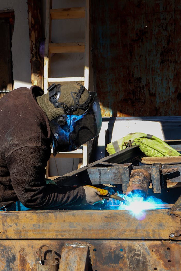 services-01 A professional welder using a welding torch in an industrial workshop, emitting bright blue sparks.